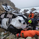 Two rescue workers inspect the crashed Tesla.
